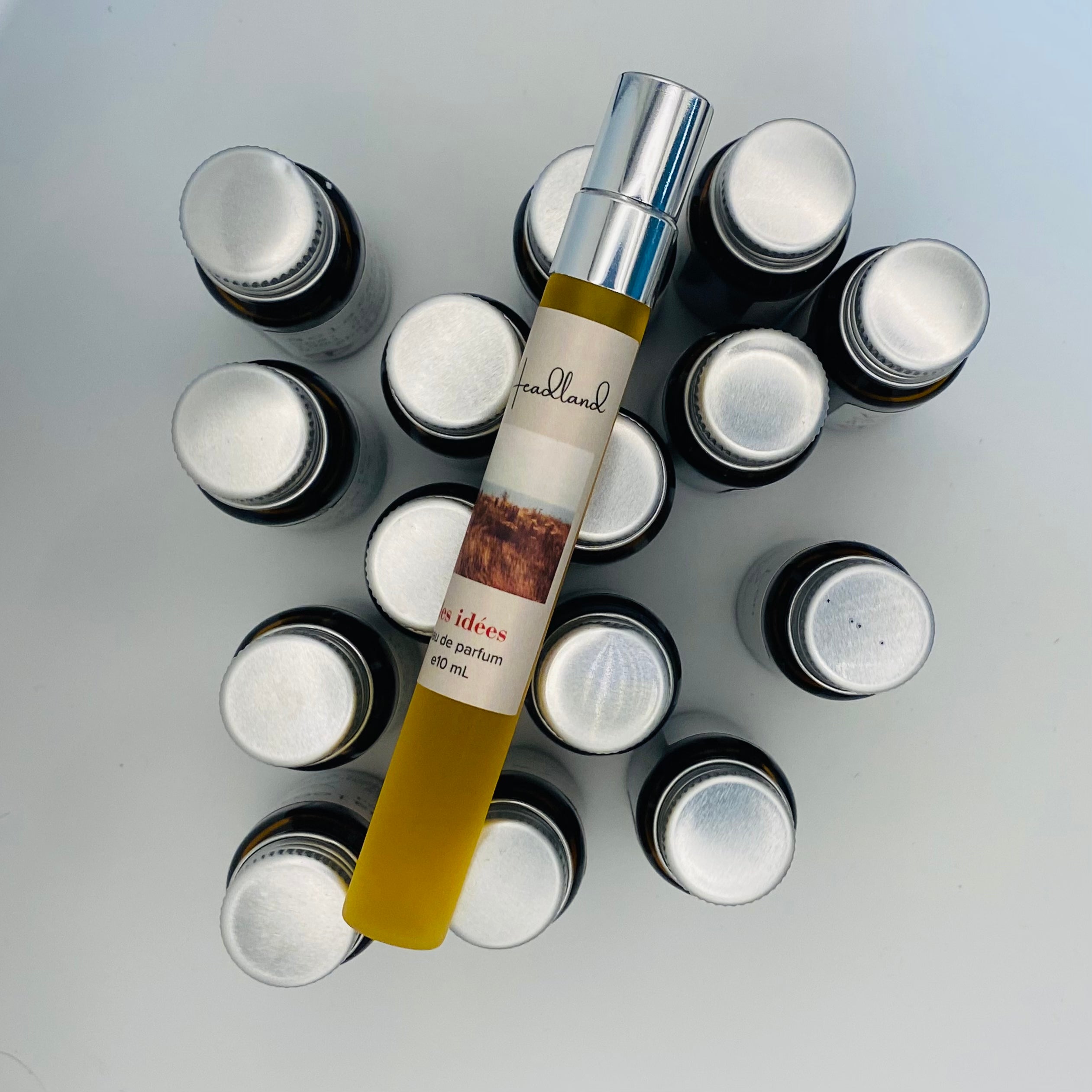 Collection of small bottles with a central tube labeled 'Headland' on a light gray background