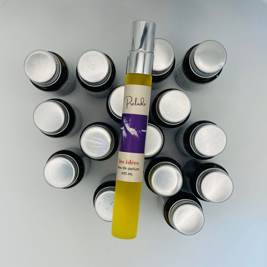 Collection of small bottles with a central tube labeled 'Prelude' on a light gray background